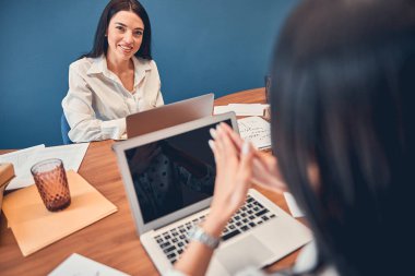 İki kadın ofiste oturuyor ve birlikte çalışıyorlar.