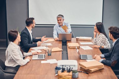 Mutlu iş arkadaşları ofiste patronla yeni başlangıç projesini tartışıyor.