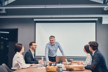 Gülümseyen meslektaşlar ofiste patronla yeni başlatılan projeyi tartışıyor