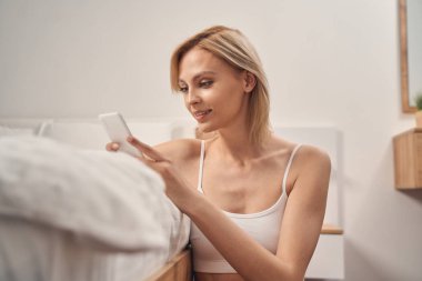 Ellerindeki akıllı telefona bakan bir kadın.