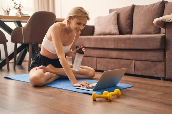 Mulher em uma pose de lótus olhando para a tela de seu laptop — Fotografia de Stock