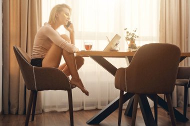 Beyaz kadın tele-işçi bir telefon görüşmesi yapıyor.