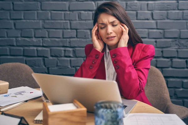 Schwerwiegende Frau leidet unter Kopfschmerzen bei der Arbeit — Stockfoto