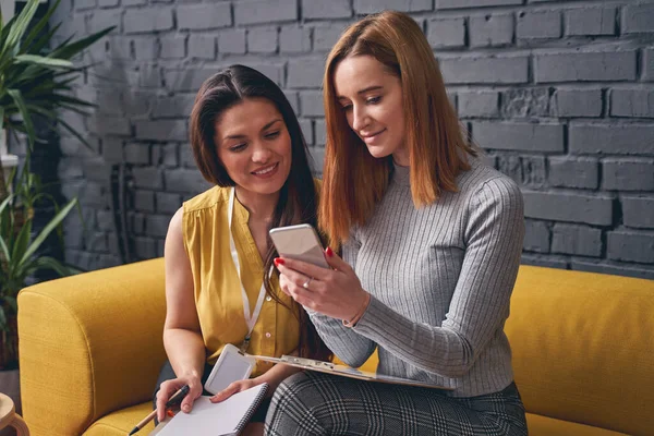 Positiv erfreute Weibchen beim Anblick von Fotos am Telefon — Stockfoto