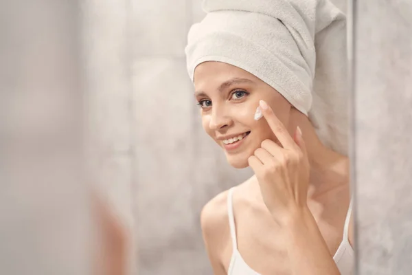 Hembra hidratando su piel con un producto cosmético — Foto de Stock