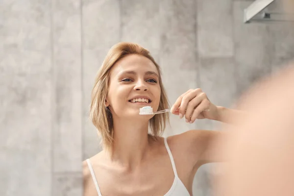 Piacevole signora pulizia dei denti in bagno — Foto Stock