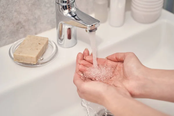 Schröpfende weibliche Handflächen unter dem Badezimmerhahn — Stockfoto