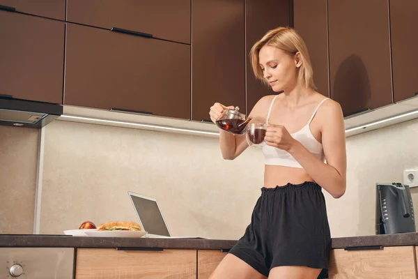 Señora enfocada vertiendo té en una taza — Foto de Stock