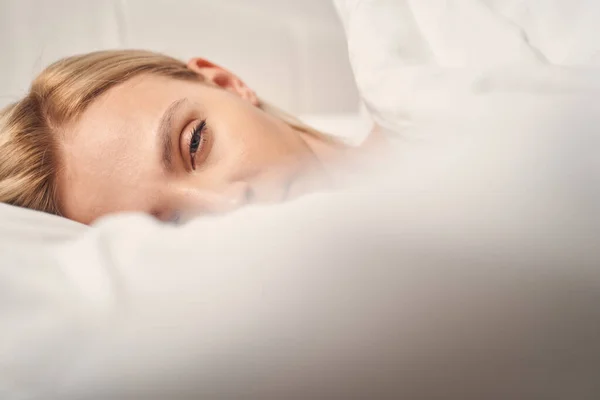 Mulher loira sonolenta na cama olhando para a frente — Fotografia de Stock