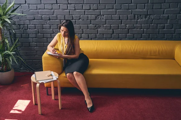 Attraktiv ung kvinna sitter på soffan i hallen — Stockfoto