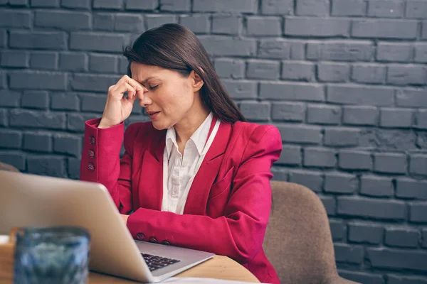 Vyčerpaná brunetka žena sedí na svém pracovišti — Stock fotografie