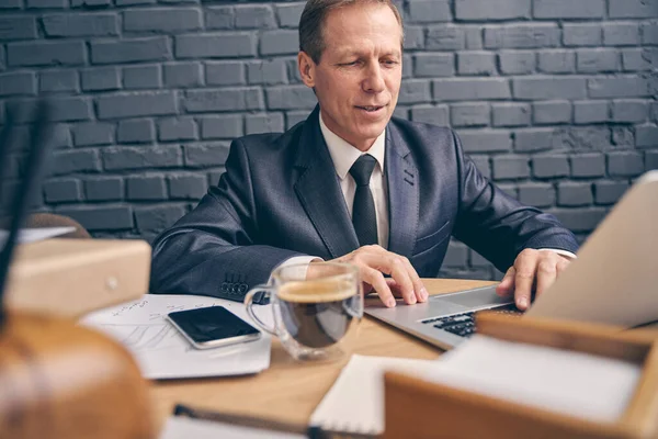 Nöjd man som sitter framför en bärbar dator — Stockfoto