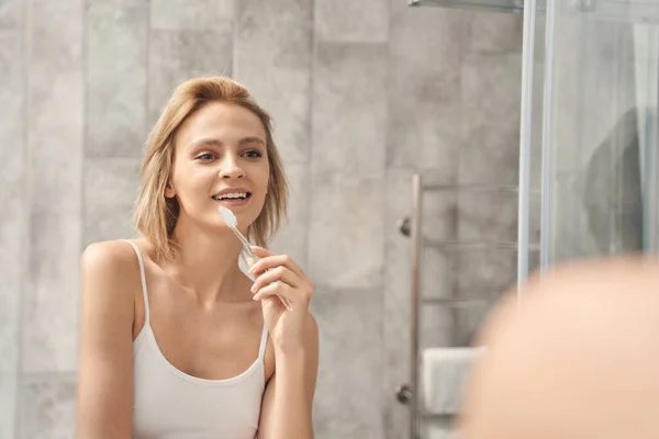 Χαμογελώντας νεαρή λευκή γυναίκα βουρτσίζει τα δόντια της — Φωτογραφία Αρχείου