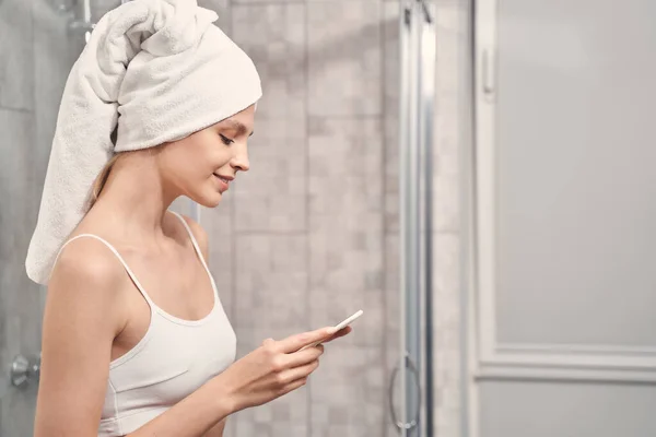 Femme regardant son smartphone dans la salle de bain — Photo