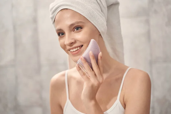 Senhora usando uma escova de limpeza facial sônica — Fotografia de Stock