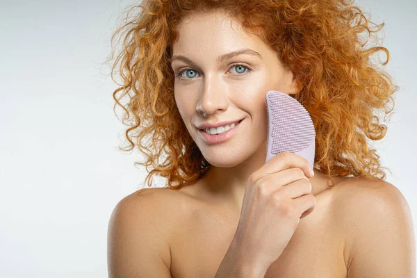 Feliz joven mujer roja haciendo masaje facial — Foto de Stock