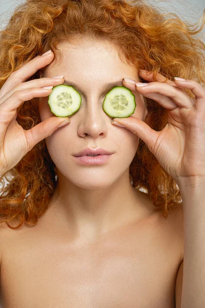 Curly female using cucumber as eye patches — Stock Photo, Image
