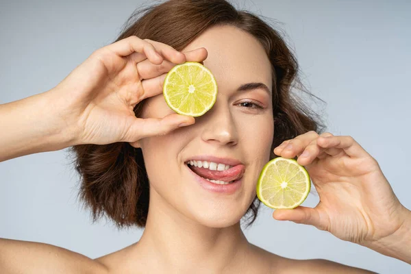 Jolly giovane donna in possesso di metà di calce intorno al viso — Foto Stock