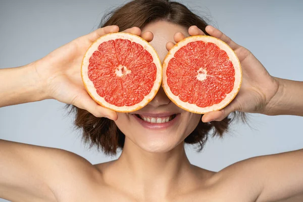 Veselá kudrnatá žena zavírající oči s grapefruitovými částmi — Stock fotografie