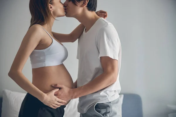 Liefdevol paar verwacht baby kussen thuis — Stockfoto