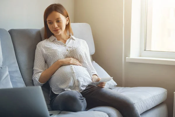 Lugn gravid kvinna med gadget på soffan hemma — Stockfoto