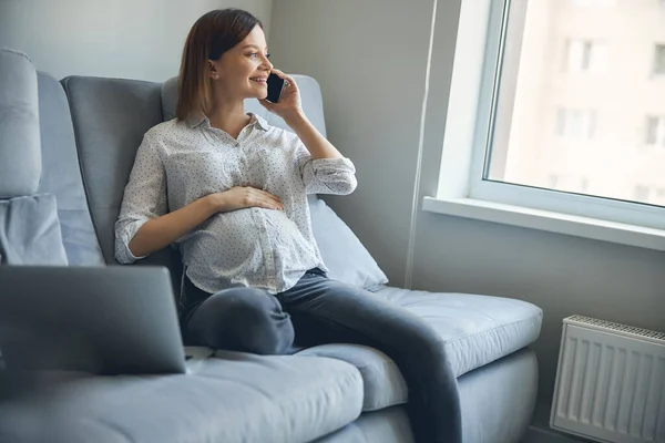 Glad gravid dam pratar i telefon hemma — Stockfoto