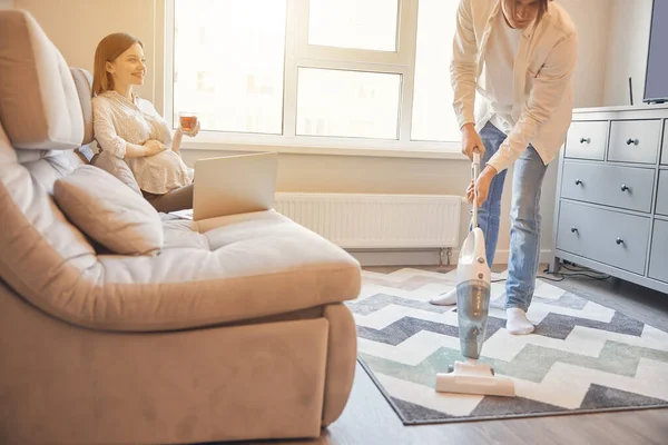 Fürsorglicher Mann erledigt Hausarbeit und hilft seiner schwangeren Frau — Stockfoto