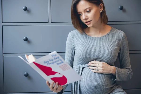 Nyugodt nő olvasás a terhesség és keres koncentrált — Stock Fotó