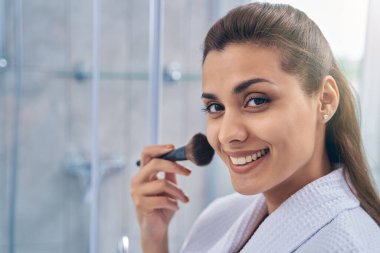 Makyaj fırçası kullanan mükemmel ciltli hoş bir bayan.