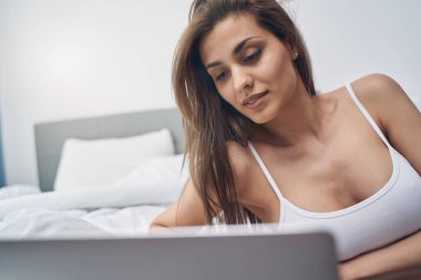 Evde dizüstü bilgisayar kullanan çekici genç bir kadın.