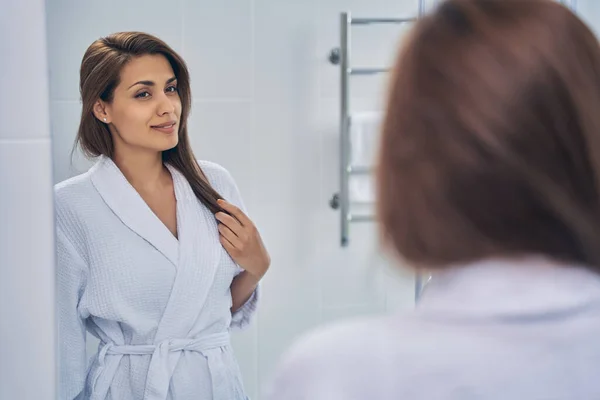 Atraktivní radostná dáma se dívá do zrcadla v koupelně — Stock fotografie