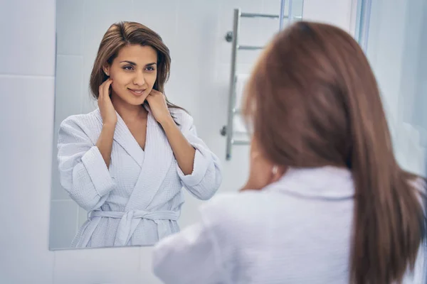 Charmig ung kvinna tittar i spegeln på morgonen — Stockfoto