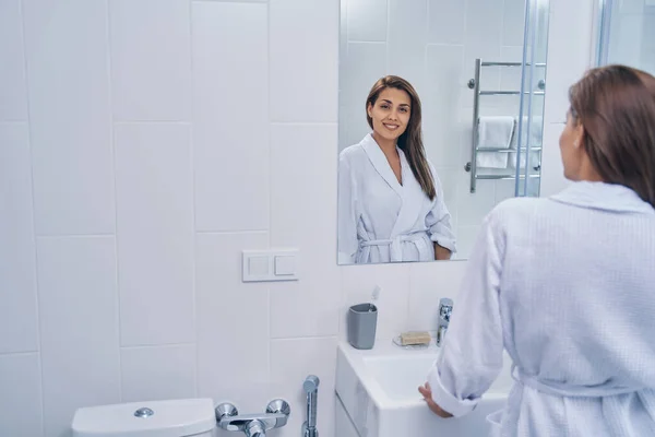 Atractiva dama de pie frente al espejo en el baño — Foto de Stock