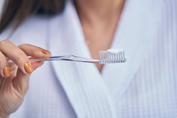 女性の手は歯磨き粉とプラスチック透明歯ブラシを保持 — ストック写真