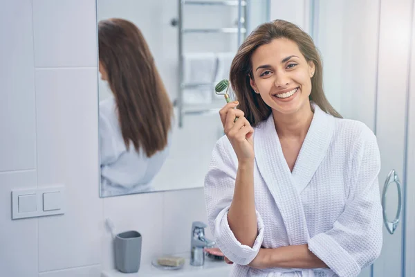 Vonzó fiatal nő használ arcmasszázs a fürdőszobában — Stock Fotó