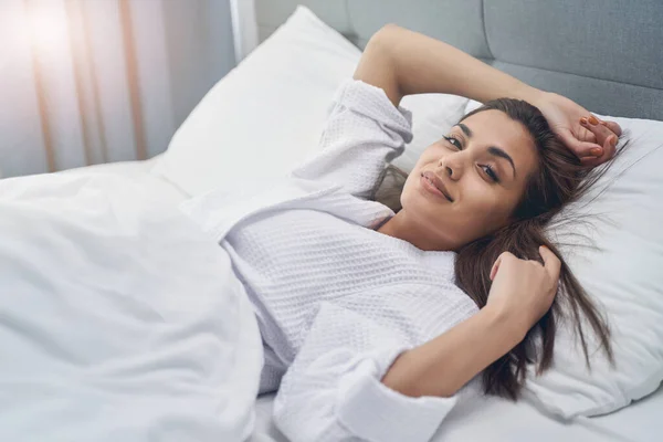 Очаровательная молодая женщина лежит в постели дома — стоковое фото