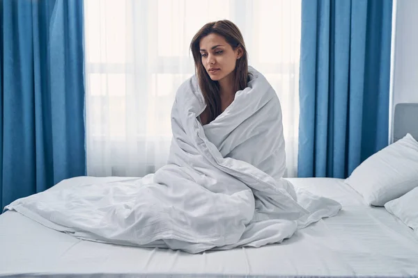 Jovem perturbada sentada na cama em casa — Fotografia de Stock