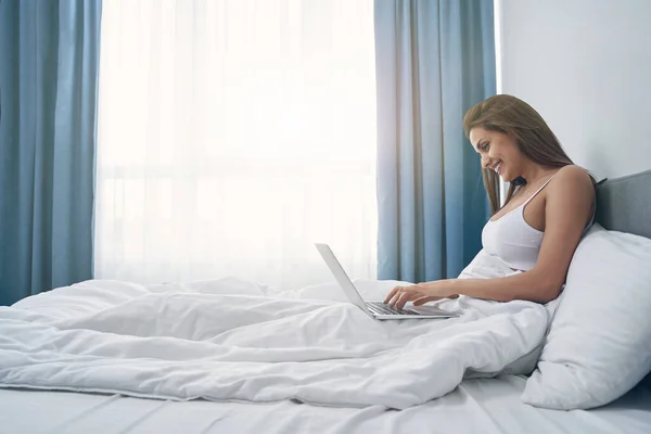 Jovem alegre usando laptop no quarto — Fotografia de Stock