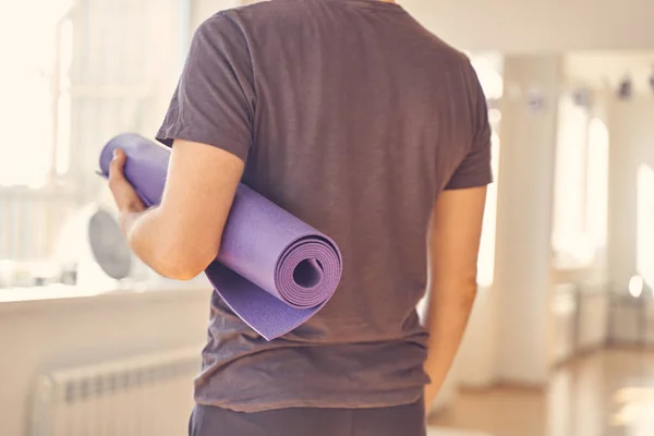 Молодий чоловік у сорочці тримає йогу килимок — стокове фото