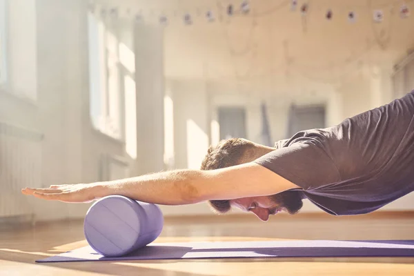 Joven haciendo ejercicio con rodillo de espuma de yoga —  Fotos de Stock