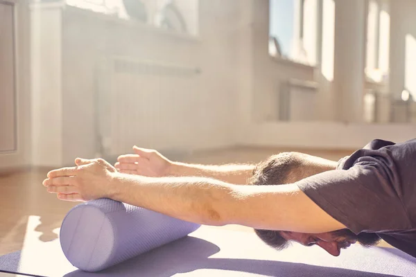 Joven sereno haciendo ejercicio con bloque de rodillos de yoga —  Fotos de Stock