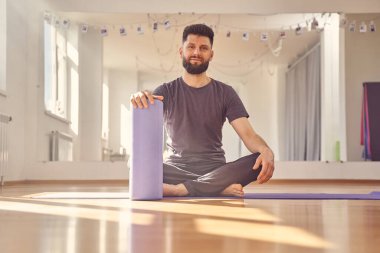 Yoga stüdyosunda yerde oturan yakışıklı genç adam.