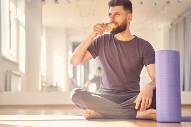 Yoga stüdyosunda çay içen yakışıklı genç adam.