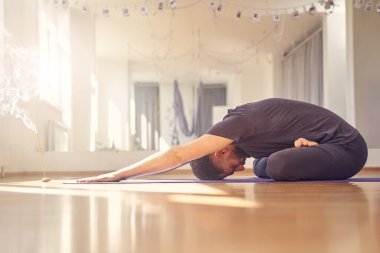 Atletik genç adam yoga stüdyosunda egzersiz yapıyor.