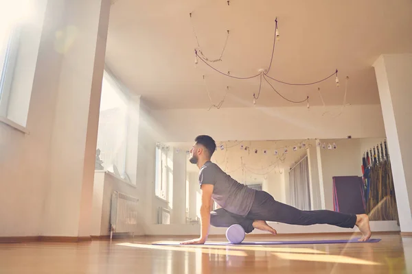 Skäggig ung man som utövar yoga i studio — Stockfoto