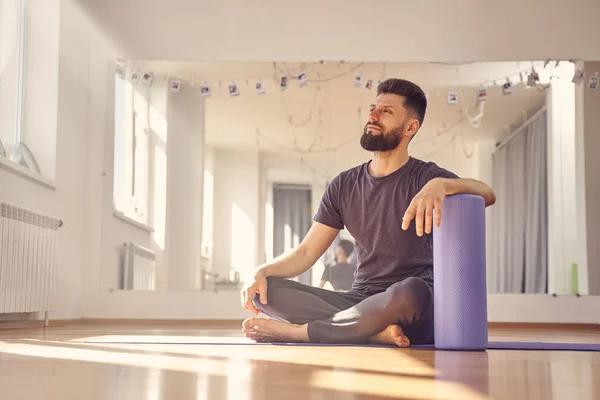 Атлетичный юноша, сидящий на полу в студии йоги — стоковое фото