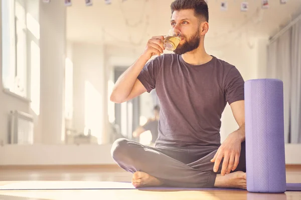 Bonito jovem bebendo chá no estúdio de ioga — Fotografia de Stock