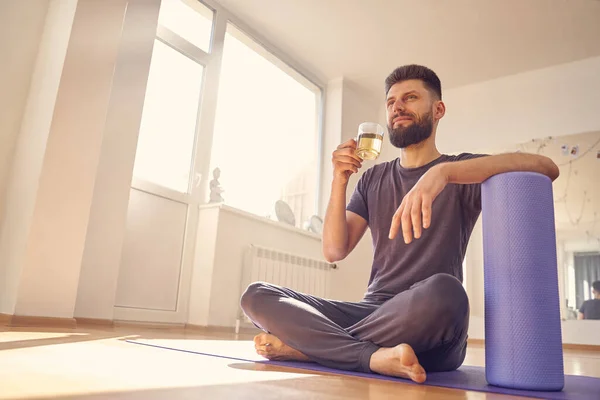 Бородатий молодий чоловік п'є трав'яний чай в студії йоги — стокове фото