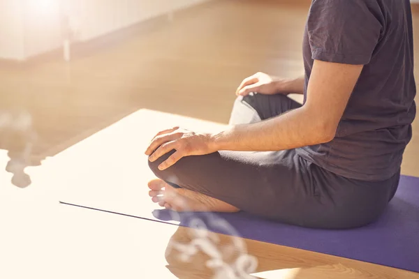 Jovem sentado no tapete de ioga na posição de lótus — Fotografia de Stock