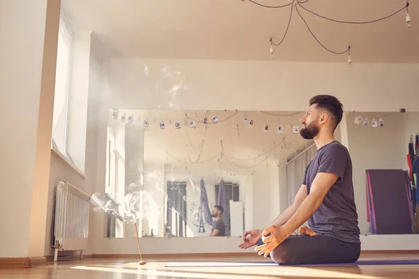 Bonito jovem meditando no estúdio de ioga — Fotografia de Stock